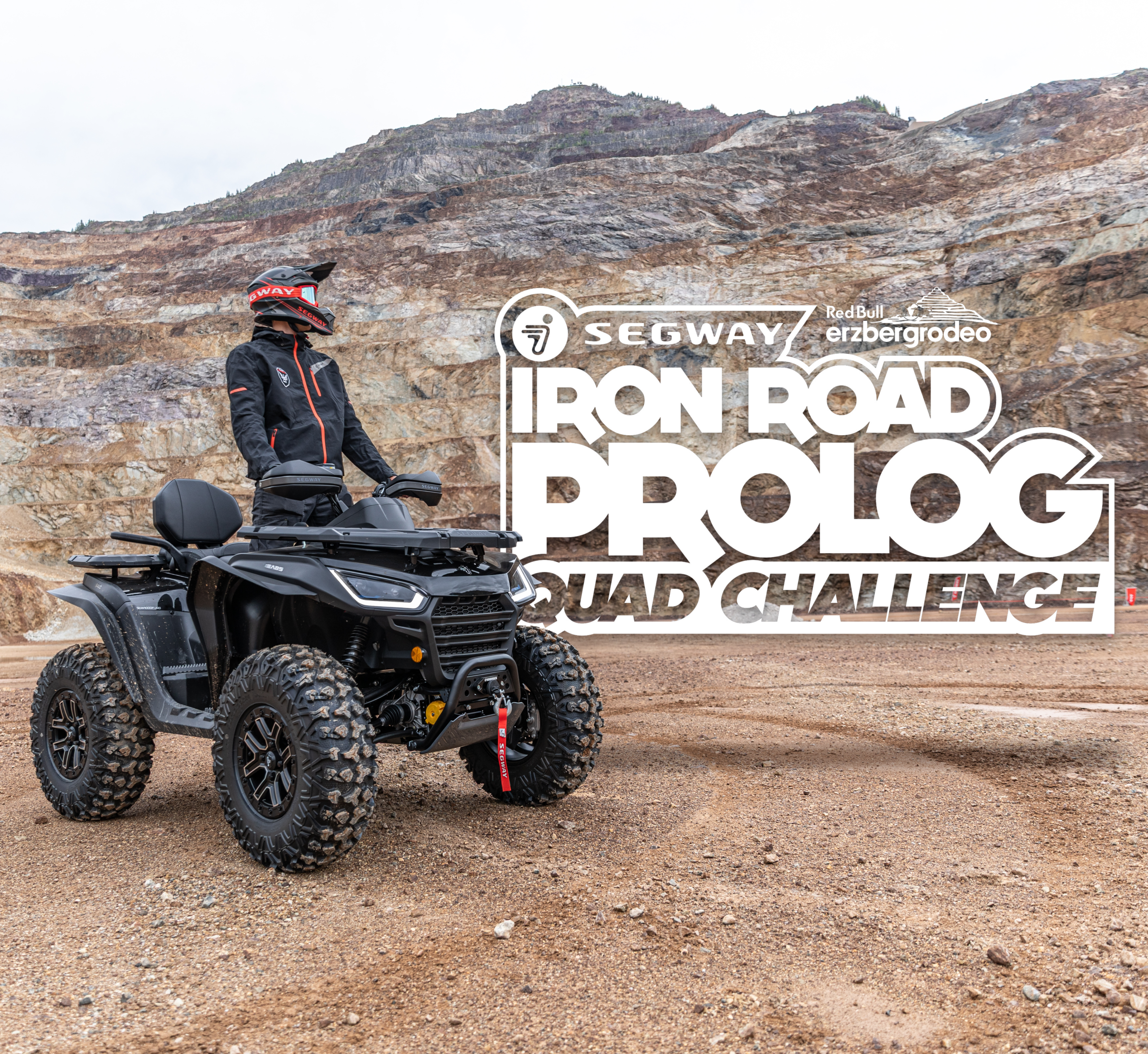 Person mit Helm und Schutzkleidung steht auf einem schwarzen Quad vor einer Felswand mit großem Schriftzug 'SEGWAY RedBull erzbergrodeo IRON ROAD PROLOG QUAD CHALLENGE'